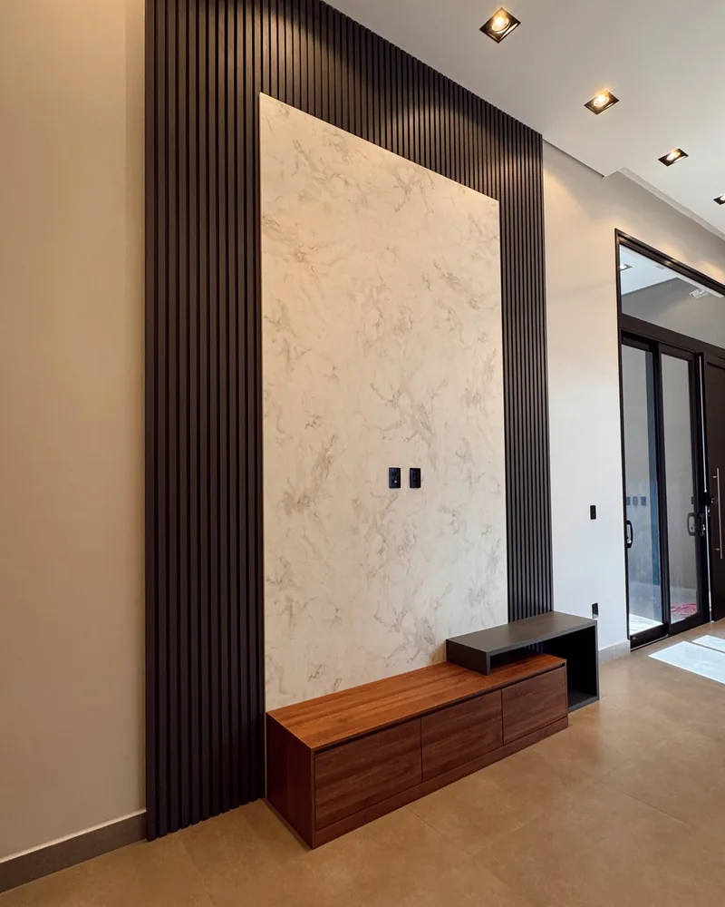 Painel ripado preto do hall, com porcelanato marmorizado e aparador suspenso em madeira